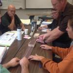 Team of workshop participants practice using an “earthquake machine” to simulate the difficulty in predicting fault slip timing and magnitude. The earthquake machine is a wood base covered in sandpaper over which wood blocks connected by rubber bands are slid.